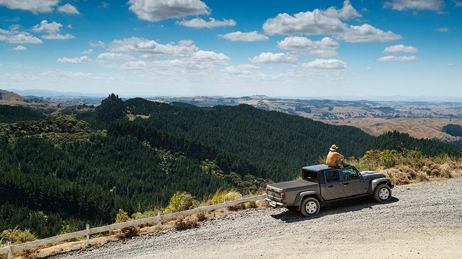 2021 Jeep Gladiator Sport parked on hilltop with man sat on roof admiring view