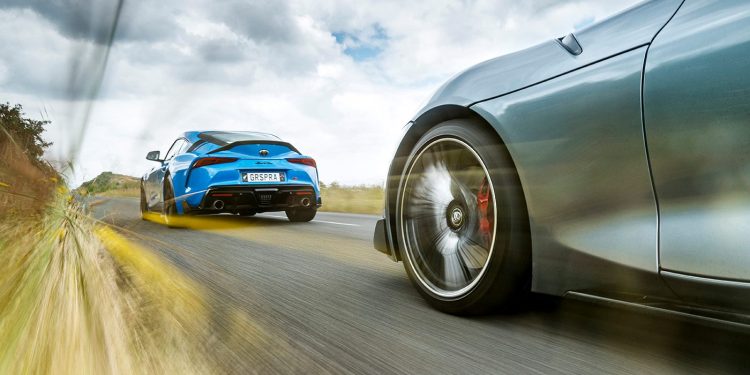 Two Toyota GR Supras driving on road