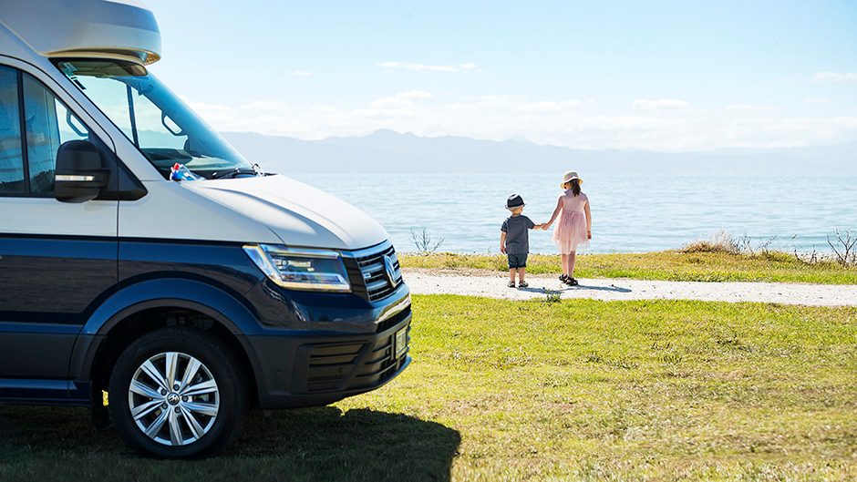 2020 Volkswagen Grand California 600 parked by sea with kids in background