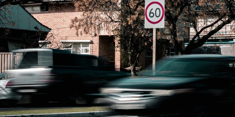 Cars driving past speed limit sign