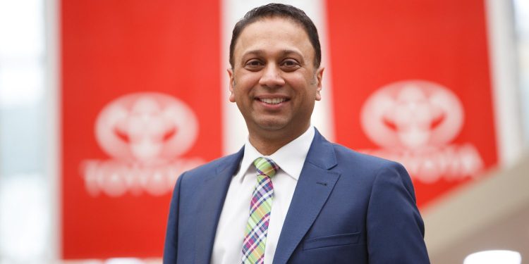 Neeraj Lala, Toyota New Zealand CEO standing in front of Toyota flags