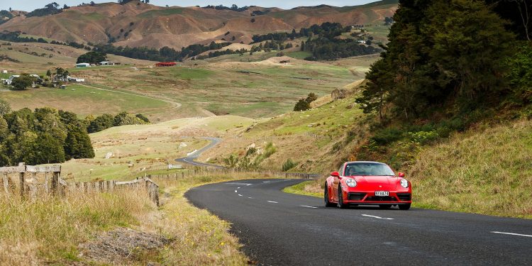 red Porsche 911 GTS driving through hills