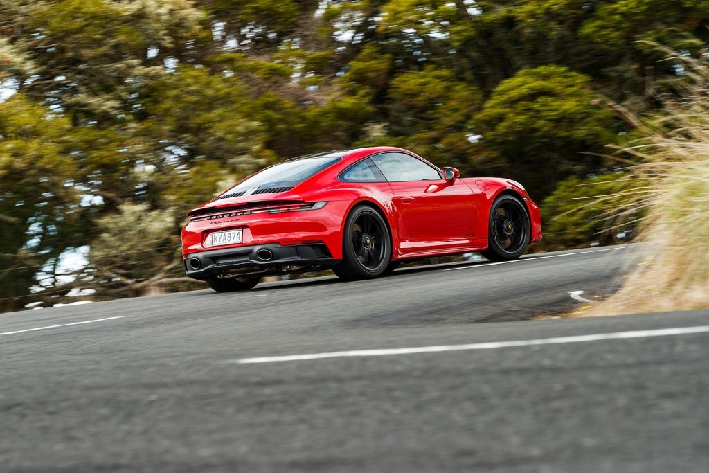 red Porsche 911 GTS rear driving action through corner