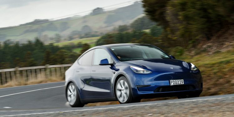 Tesla Model Y front three quarter view driving on road