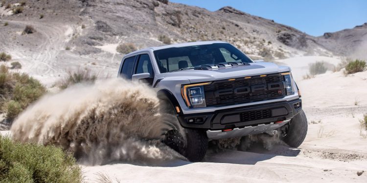 Ford F-150 Raptor R driving through sand in desert front three quarters