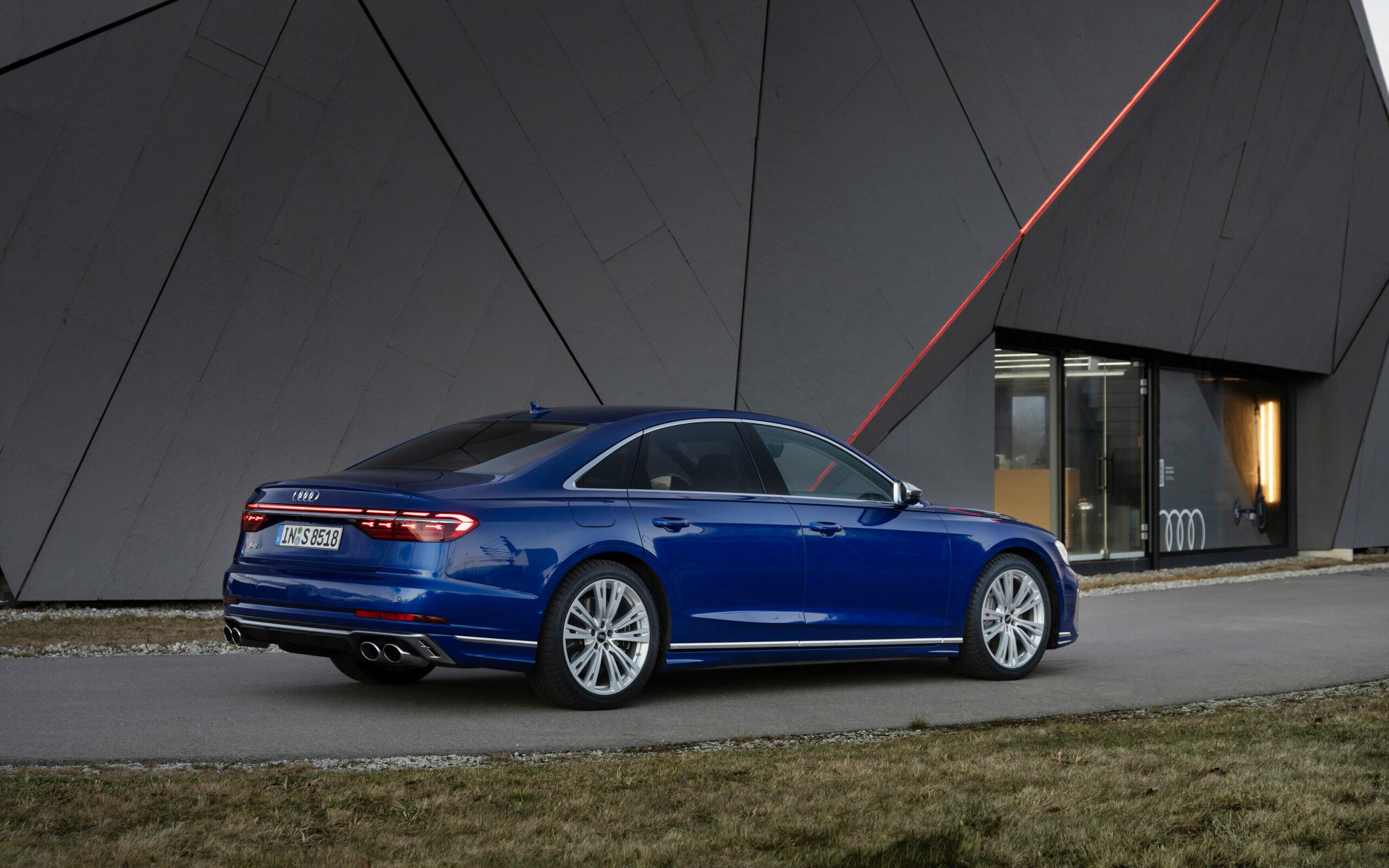 Audi S8 performance sedan rear three quarters next to building