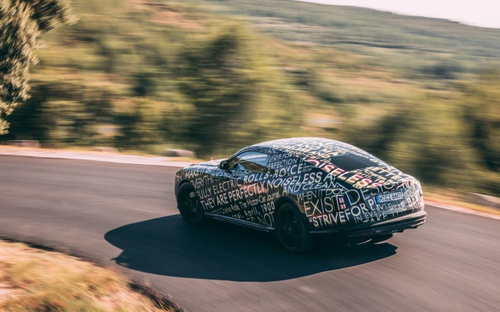 Rolls-Royce Spectre EV camouflaged driving around corner rear three quarters