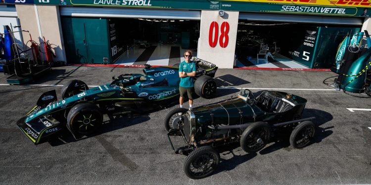 Sebastian Vettel standing between AMR22 Formula 1 car and 1922 Aston Martin TT1 Green Pea