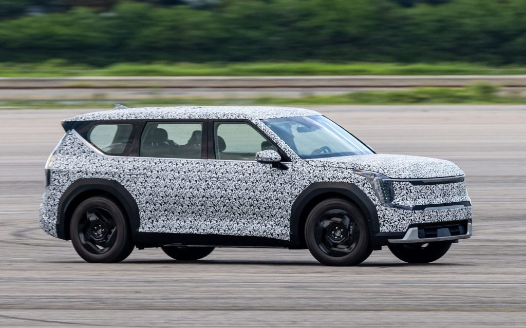 Kia EV9 in camouflage driving on test track side view