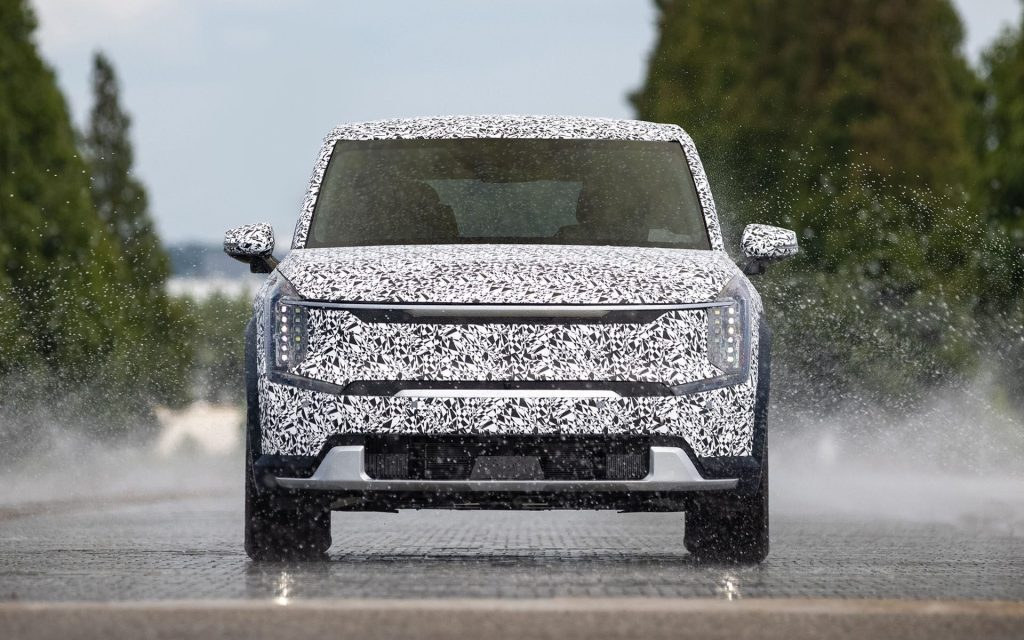 Kia EV9 in camouflage driving on test track front view