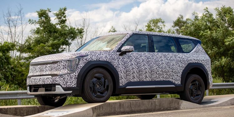 Kia EV9 in camouflage driving on obstacle front three quarter view