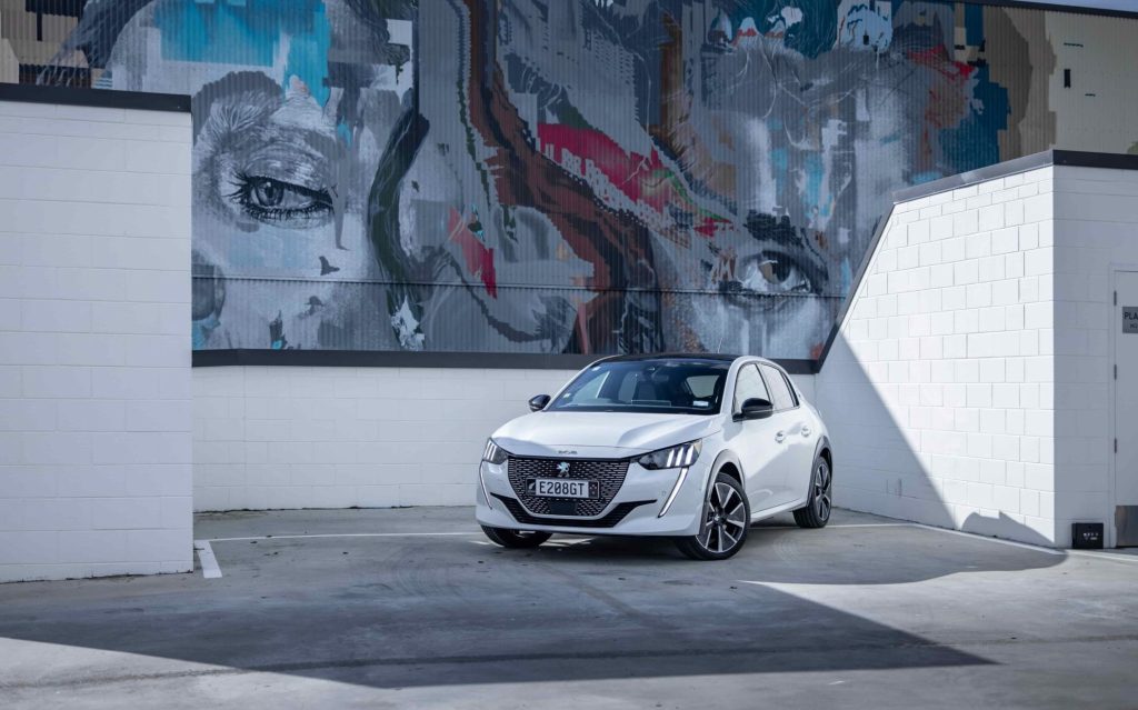 Peugeot e-208 GT front three quarters in front of mural