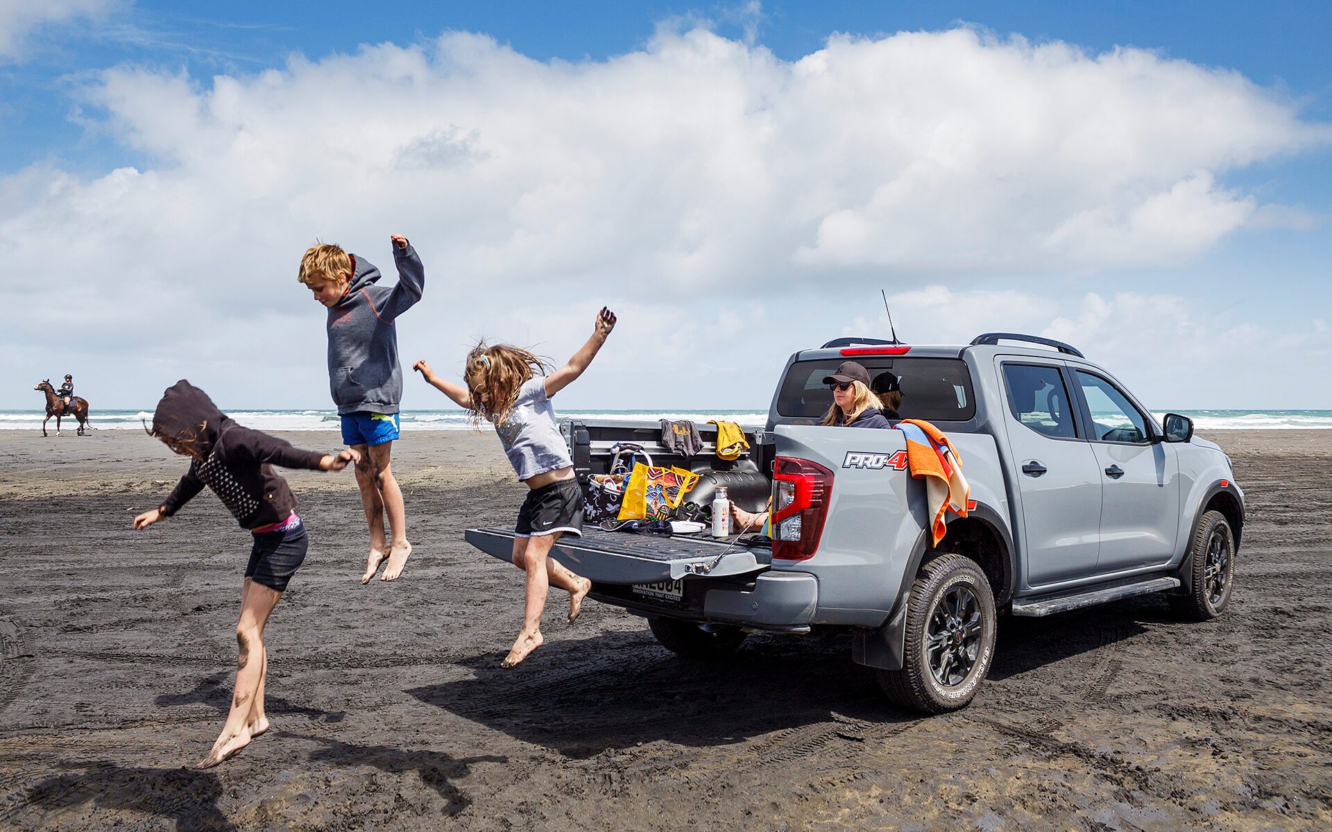 Kids jumping off back of Nissan Navara at Muriwai Beach