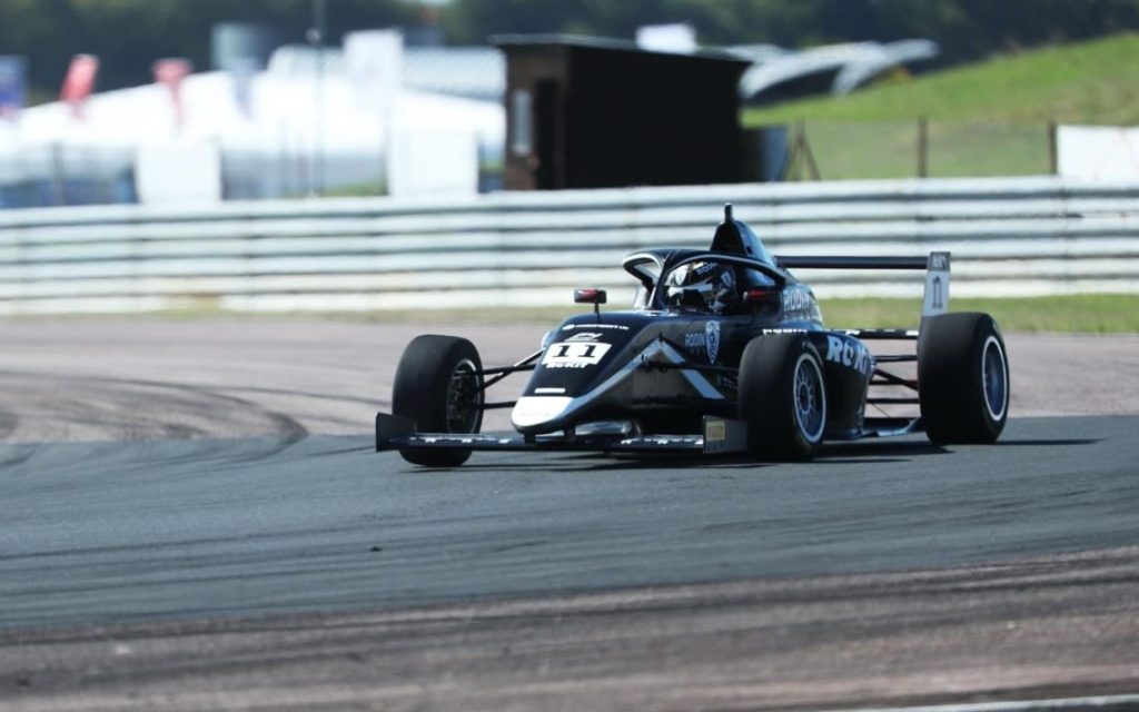 Formula 4 car racing on track front three quarter view