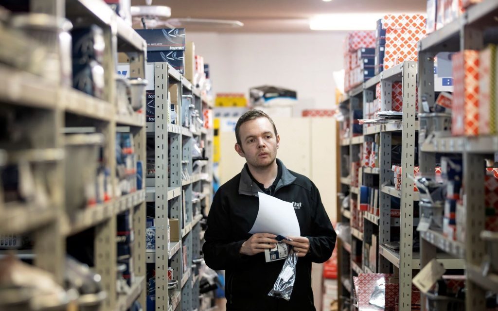 Qualitat mechanic walking through parts aisle