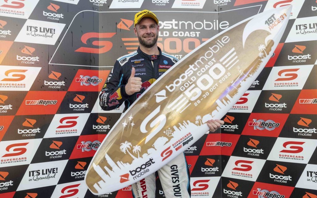 Shane van Gisbergen holding surf board trophy