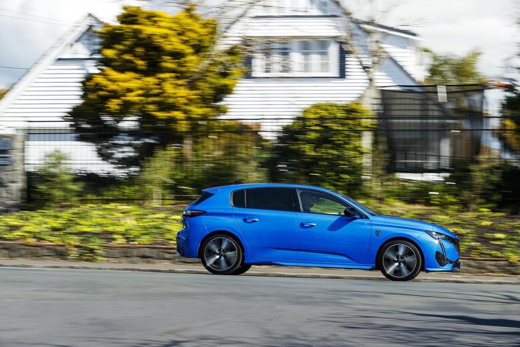 Peugeot 308 driving past houses