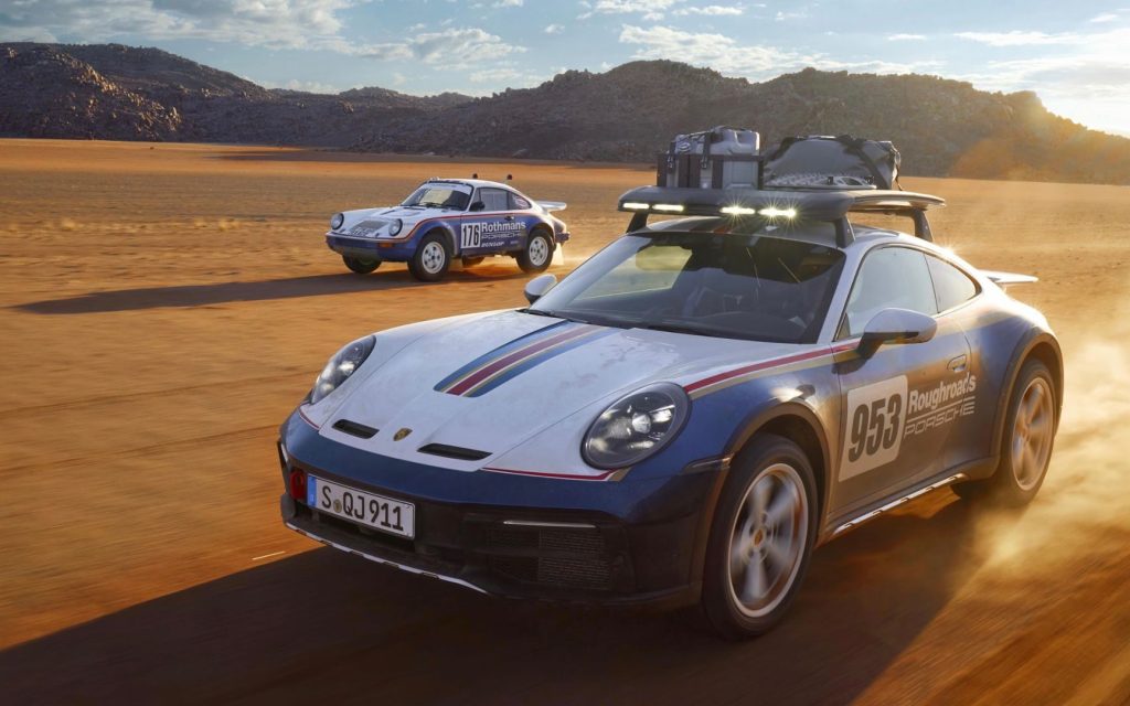 Porsche 911 Dakar driving next to 1984 rally car front three quarter view