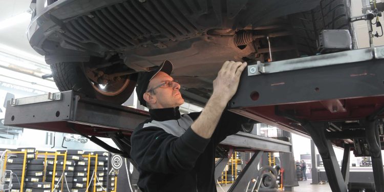 Worker inspecting underneath a car