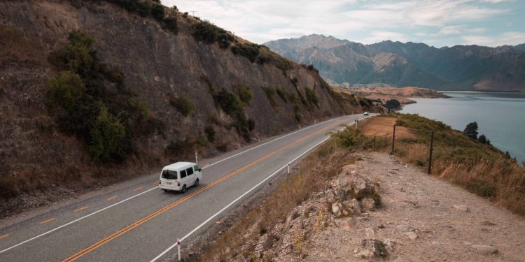 Van driving on road by lake