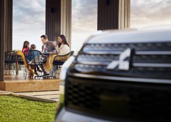 Family sitting at table with Mitsubishi Outlander in foreground