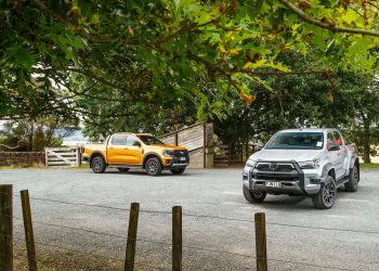 Ford Ranger Wildtrak vs Toyota Hilux SR5 Cruiser front static with fenc ein foreground