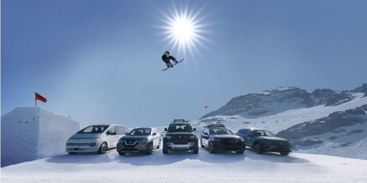 Snowboarder jumping row of cars