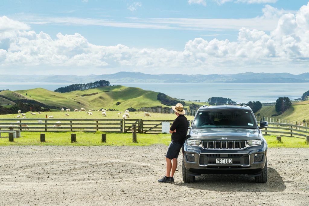 Jeep GC Overland parked up on a hill, looking out to a number of sheep