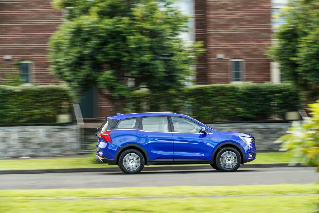 Fly-by side profile shot of the Mahindra driving in suburbia