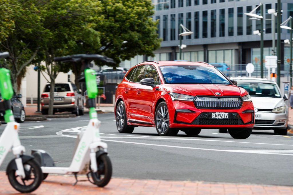 Red Skoda Enyaq Sportline 80 iV takes a corner in a city setting