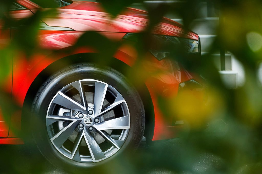 Detail shot of the Enyaq's wheel, taken through tree leaves