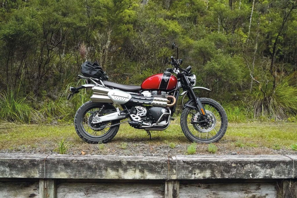 Red Triumph Scrambler 1200 XC parked in a scenic setting 