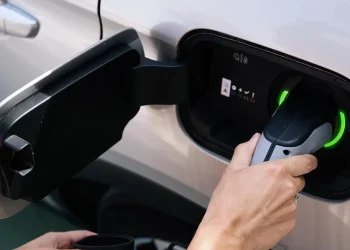 Person plugging charging cable into electric vehicle