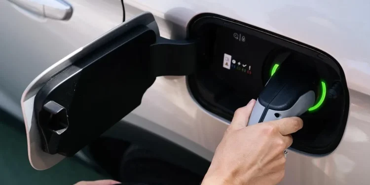 Person plugging charging cable into electric vehicle
