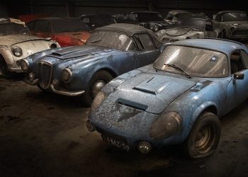 Old cars covered in dust parked in warehouse