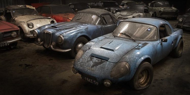 Old cars covered in dust parked in warehouse