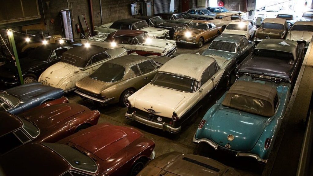 Old cars covered in dust parked in warehouse