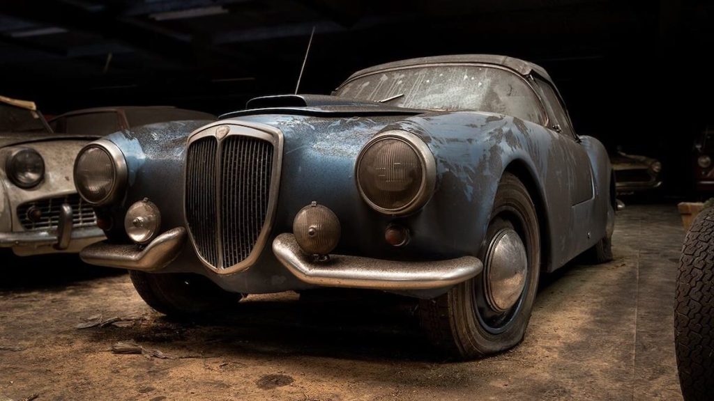 Old Lancia covered in dust parked in warehouse