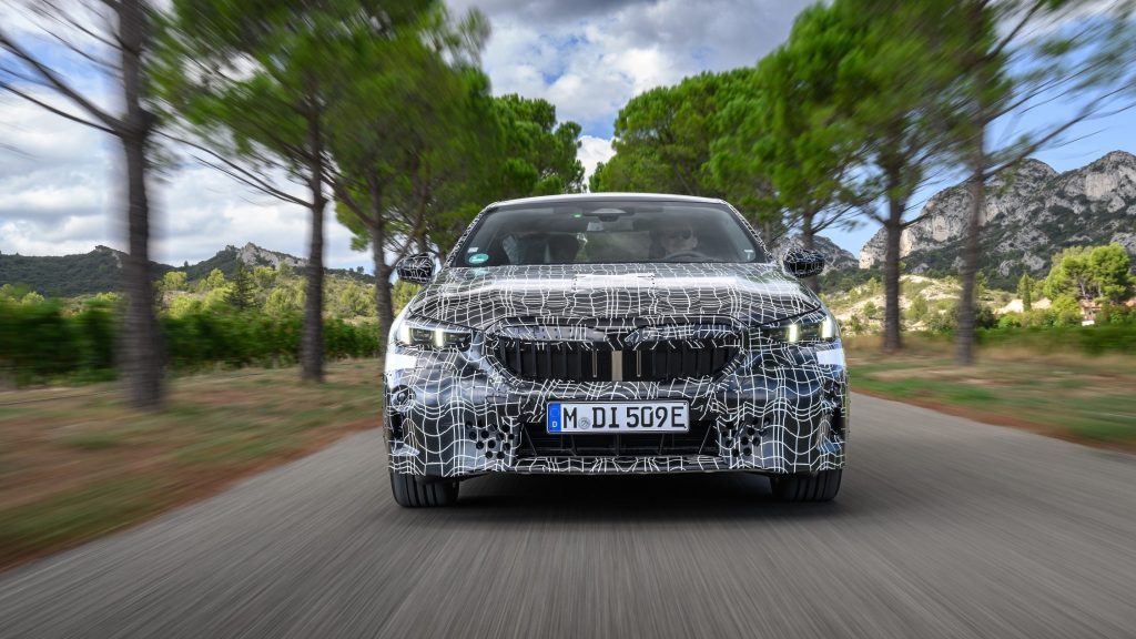 BMW i5 camouflaged front view driving