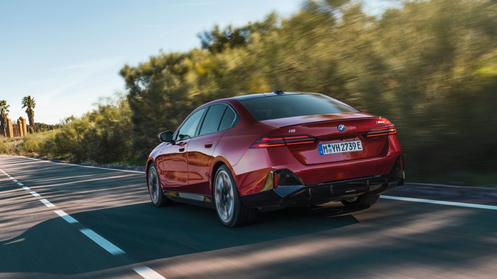 BMW i5 M60 xDrive driving past trees