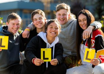 Teenagers holding learner driver plates