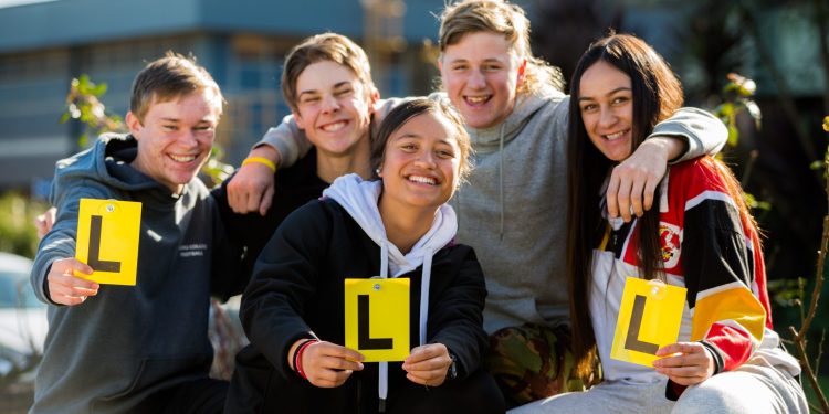 Teenagers holding learner driver plates