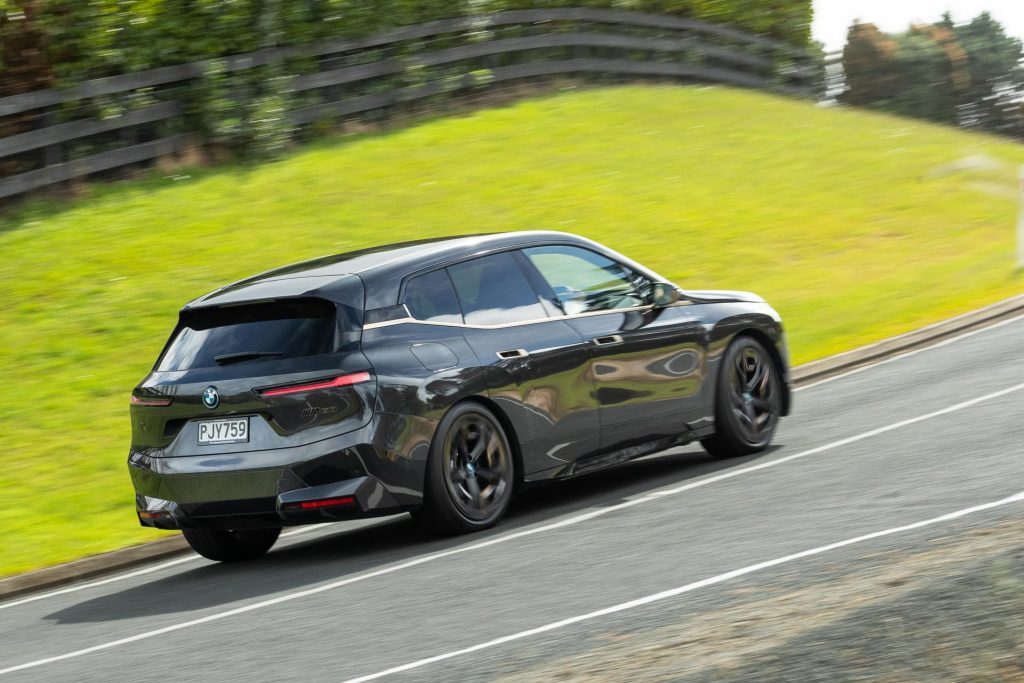 BMW iX M60 driving up a hill with the rear in view