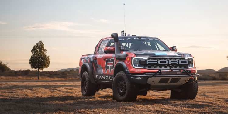 Ford Ranger Raptor race truck parked in field by tree