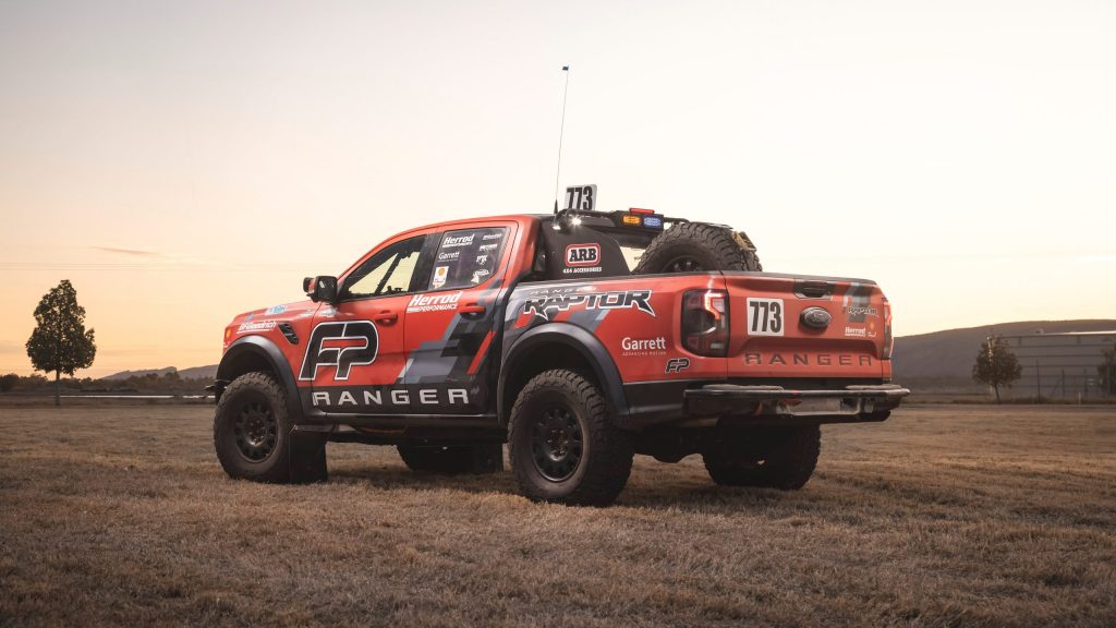 Ford Ranger Raptor race truck parked in field by tree