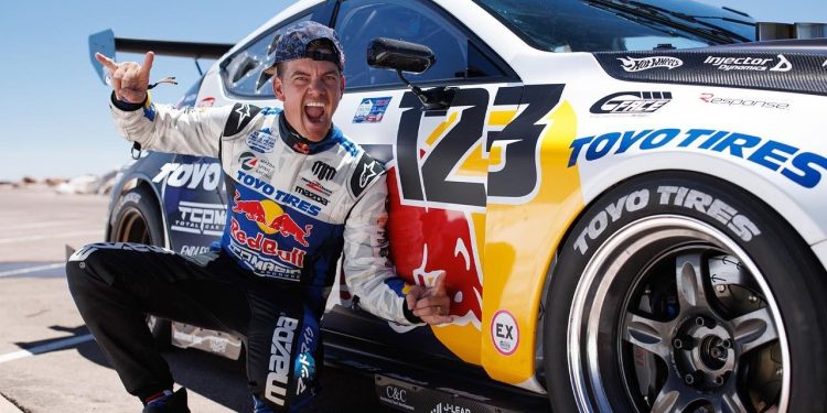 Mad Mike Whiddett posing next to Mazda3 Pikes Peak car