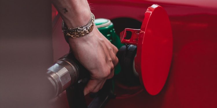 Person filling red car up with petrol