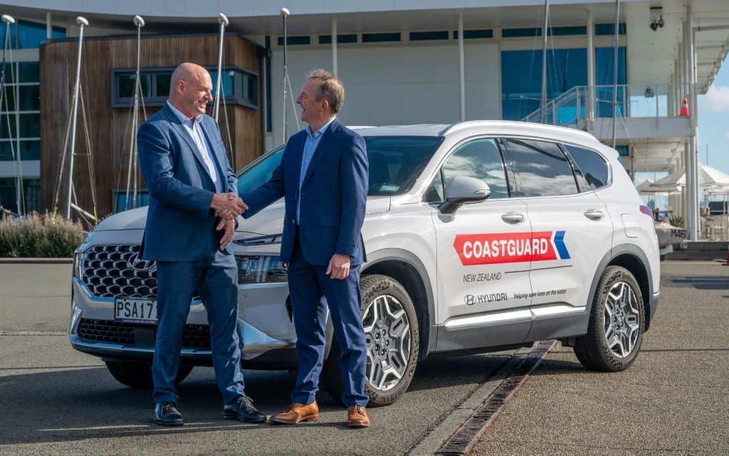 Two men shaking hands in front of Hyundai Santa Fe with Coastguard New Zealand livery