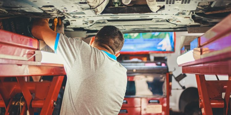 Man inspecting underside of car