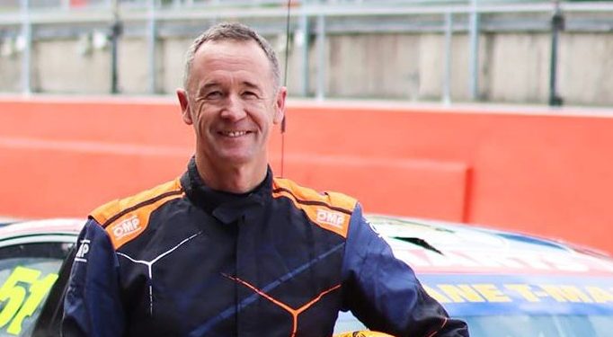 Greg Murphy standing with helmet in arms